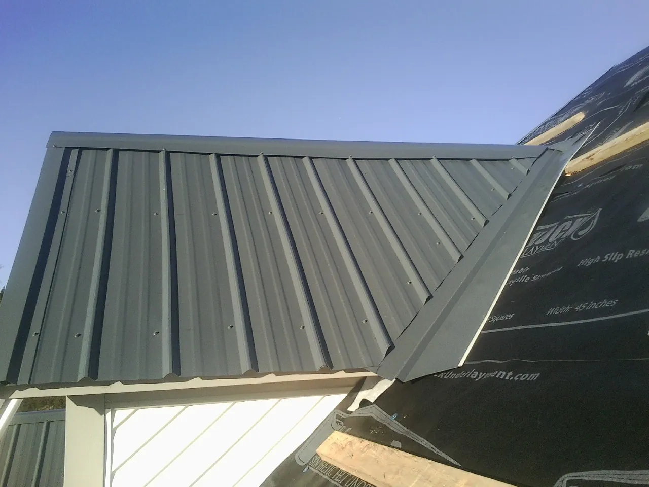 Gray metal roof panels going on over a garage gable in Rancho Cucamonga