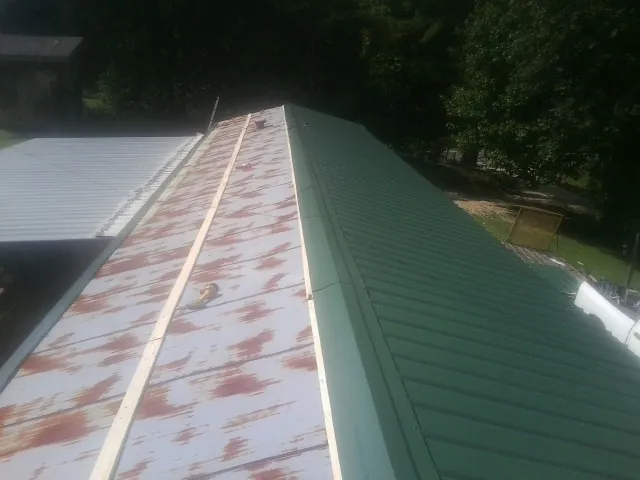 Old rusted panels beside newly installed green metal roofing — Wind Damage Roof Repair by Roofing Brothers in Rancho Cucamonga