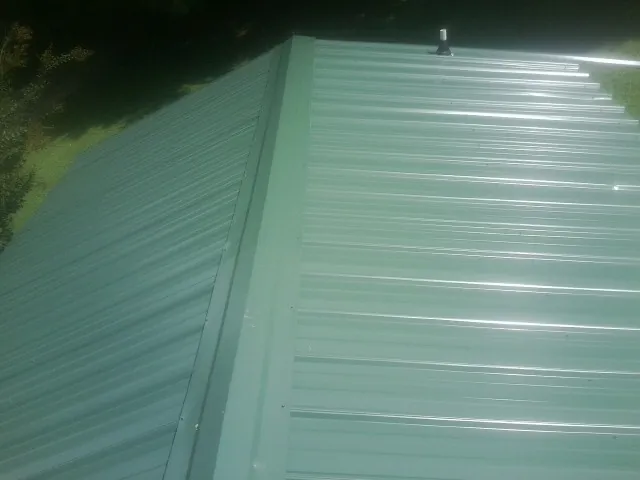 New green metal panels meeting at the ridge of a roof — Flat Roof Repair work by our crew in Rancho Cucamonga