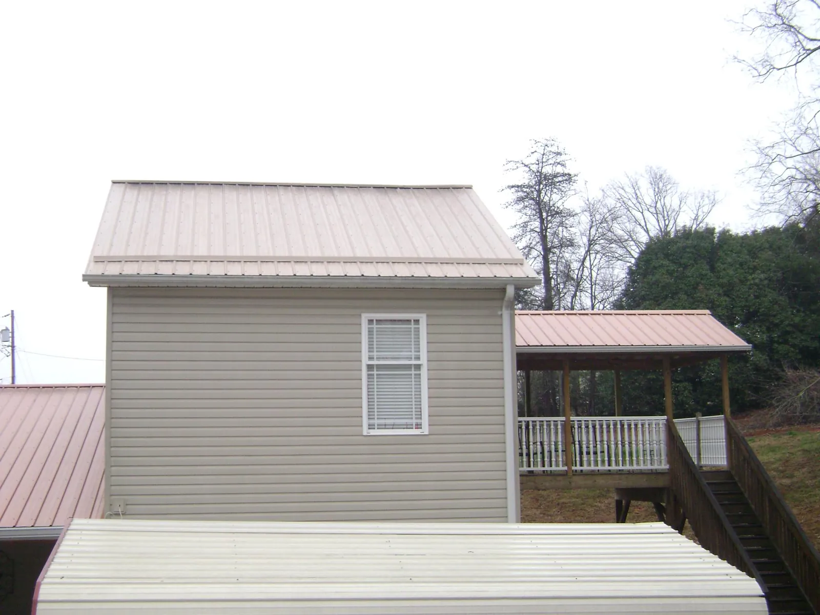 Tan metal roofs on a two story addition and attached porch, from a Roof Replacement job in Rancho Cucamonga