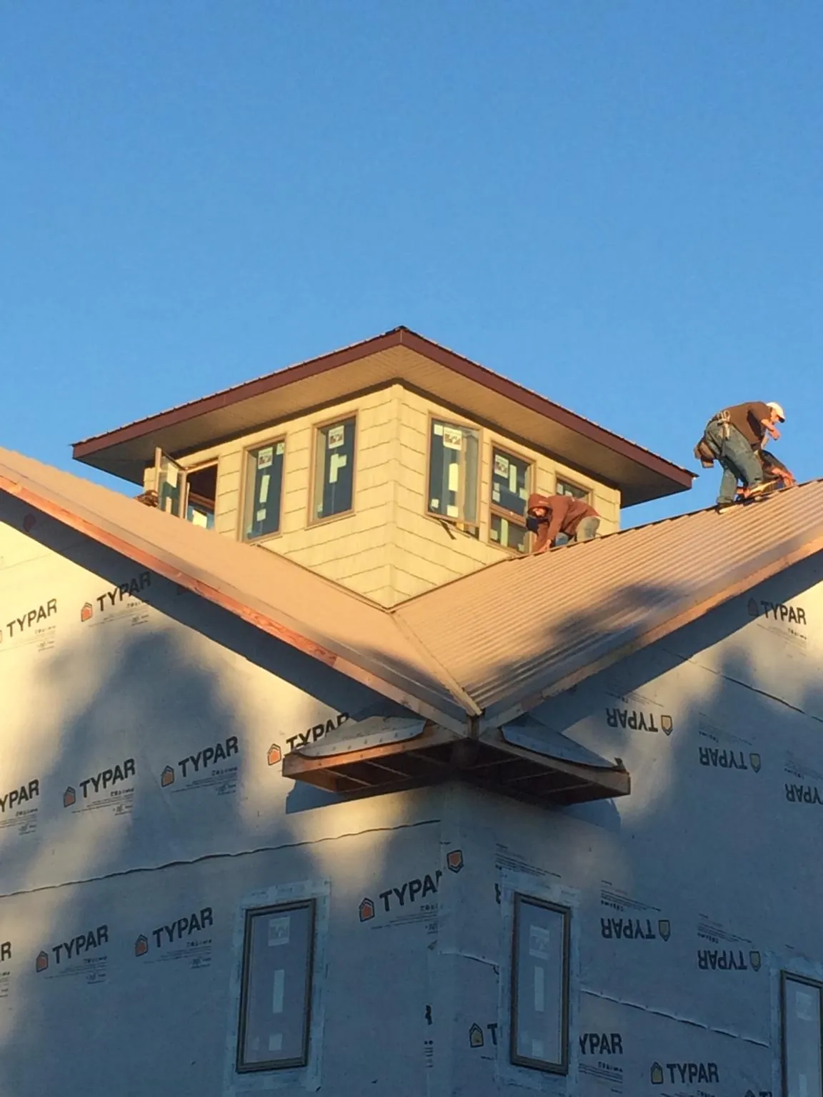 Roofers working around a rooftop cupola on a new metal roof at sunset — Roof Waterproofing in Rancho Cucamonga by Roofing Brothers
